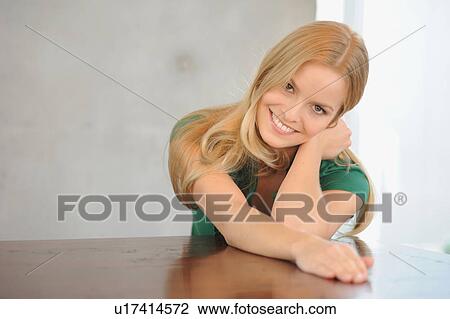 Stock Image - Smiling woman sitting at table. Fotosearch