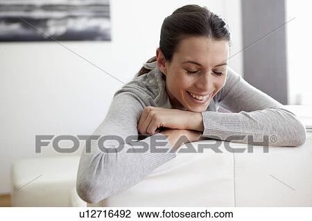 Smiling woman sitting on couch View Large Photo Image Stock Image - Smiling woman sitting on couch. Fotosearch