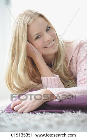 Stock Image - Smiling woman sitting on pillow. Fotosearch