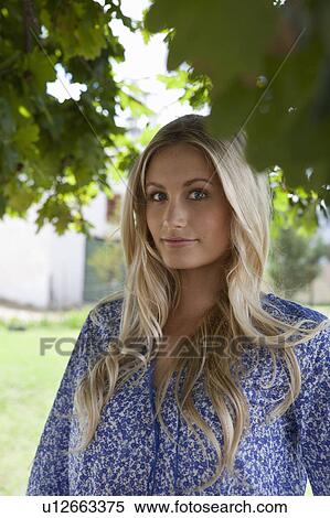 Stock Photography - Smiling woman standing under tree. Fotosearch