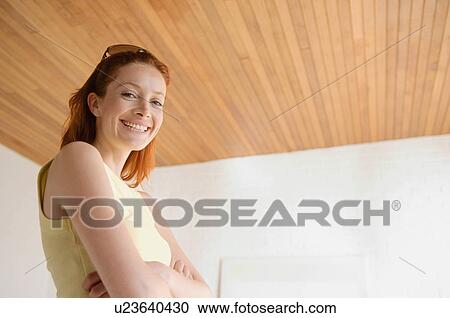 Stock Image - Smiling woman standing with arms folded. Fotosearch