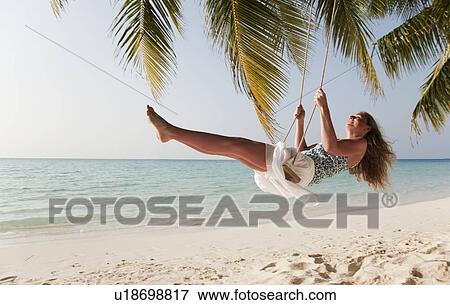 Smiling woman swinging on tropical beach View Large Photo Image Stock Photo - Smiling woman swinging on tropical beach. Fotosearch