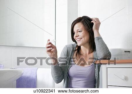 Stock Image - Smiling woman taking pregnancy test. Fotosearch
