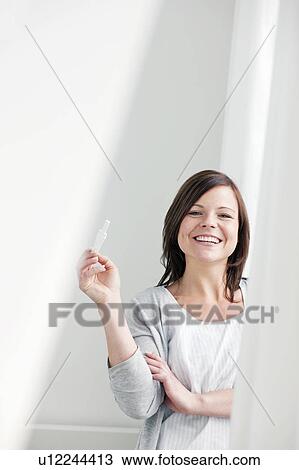 Stock Image - Smiling woman taking pregnancy test. Fotosearch