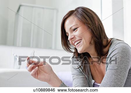 Stock Photograph - Smiling woman taking pregnancy test. Fotosearch