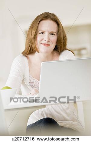 Stock Photograph - Smiling woman using laptop. Fotosearch