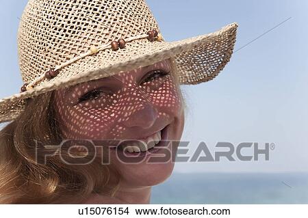Picture - Smiling woman wearing sunhat. Fotosearch