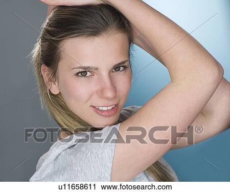 Stock Image - Smiling woman with hands in hair. Fotosearch