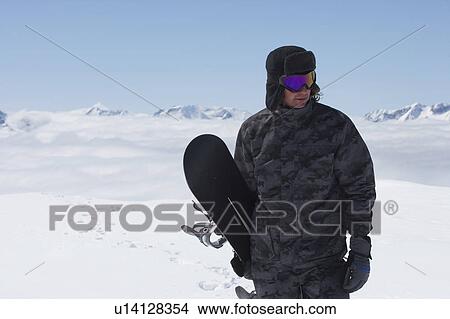 Snowboarder carrying board on slope View Large Photo Image Picture - Snowboarder carrying board on slope. Fotosearch