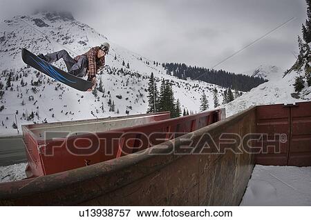 Stock Photo - Snowboarder jumping over train cars. Fotosearch