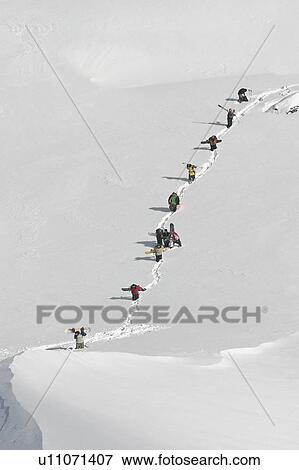 Stock Photo - Snowboarders walking up mountainside. Fotosearch