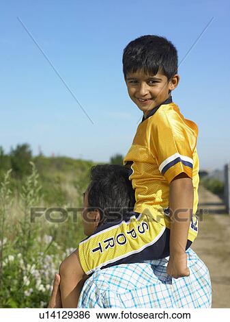 Stock Photograph - Son sitting on father’s shoulders. Fotosearch