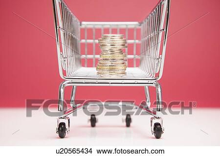 Picture - Stack of coins in shopping cart. Fotosearch