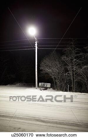 Stock Image - Streetlight over snowy road at night. Fotosearch