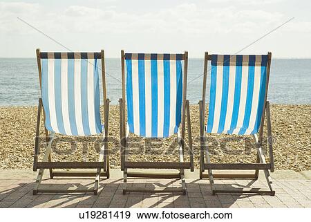 Stock Photo - Striped lawn chairs on beach. Fotosearch