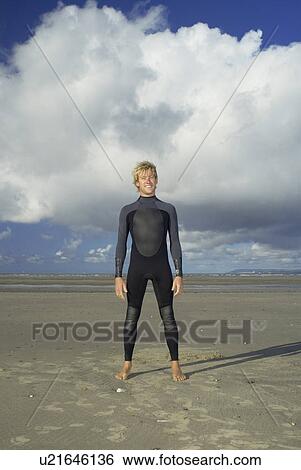 Surfer standing on beach View Large Photo Image Stock Photograph - Surfer standing on beach. Fotosearch
