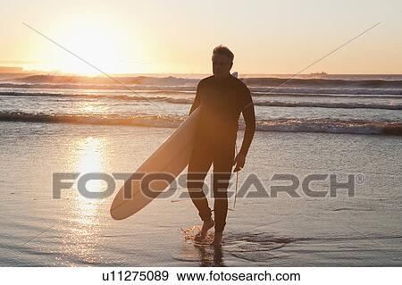 Surfer walking in water View Large Photo Image Stock Photo - Surfer walking in water. Fotosearch