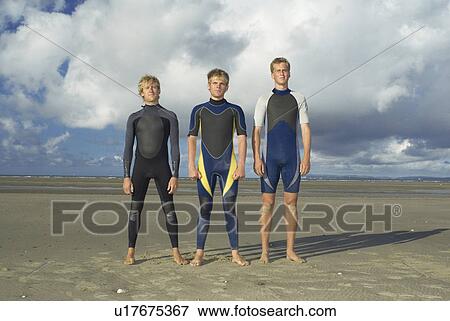 Surfers standing in row on beach View Large Photo Image Stock Photo - Surfers standing in row on beach. Fotosearch