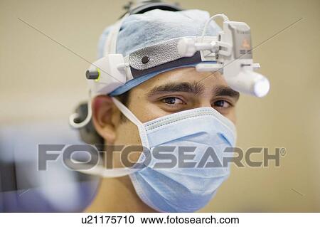 Stock Image - Surgeon wearing mask and headlamp. Fotosearch