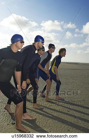 Swimmers standing in row on beach View Large Photo Image Stock Image - Swimmers standing in row on beach. Fotosearch