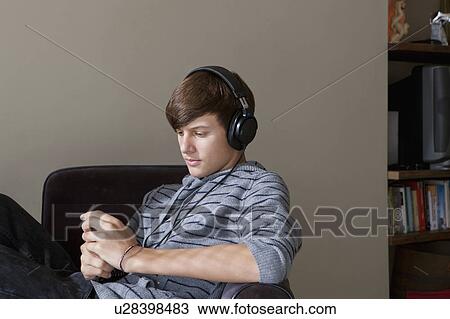Teenage boy listening to headphones View Large Photo Image Stock Image - Teenage boy listening to headphones. Fotosearch