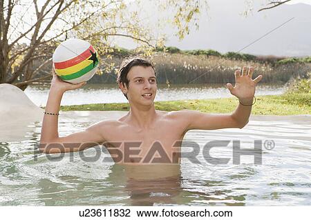 Stock Image - Teenage boy playing with ball in lake. Fotosearch