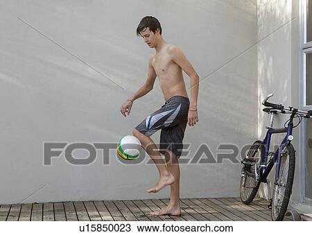Stock Image - Teenage boy playing with soccer ball. Fotosearch