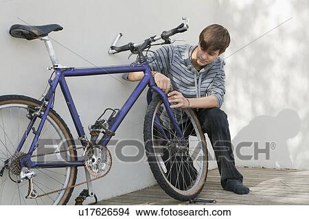 Picture - Teenage boy repairing bicycle. Fotosearch