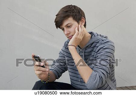 Stock Image - Teenage boy using cell phone. Fotosearch