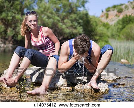 Teenage couple sitting in rocky river View Large Photo Image Stock Image - Teenage couple sitting in rocky river. Fotosearch