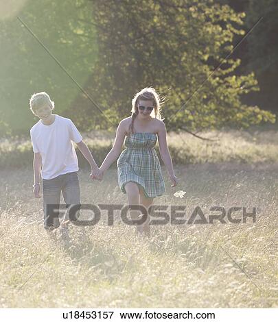 Teenage couple walking together in field View Large Photo Image Stock Photo - Teenage couple walking together in field. Fotosearch