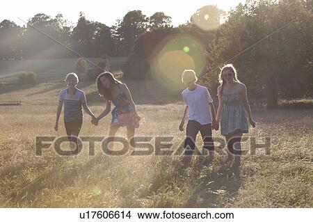 Picture - Teenage couples walking in field. Fotosearch