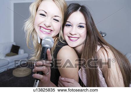 Stock Photography - Teenage girls singing karaoke. Fotosearch