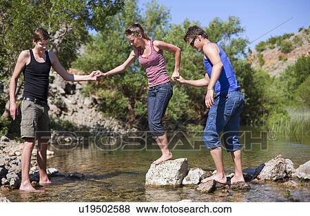 Teenagers crossing rocky river View Large Photo Image Stock Photo - Teenagers crossing rocky river. Fotosearch