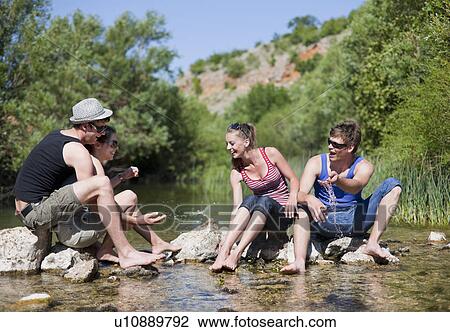 Teenagers sitting in rocky river View Large Photo Image Stock Image - Teenagers sitting in rocky river. Fotosearch