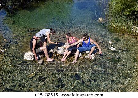 Teenagers sitting in rocky river View Large Photo Image Stock Photography - Teenagers sitting in rocky river. Fotosearch
