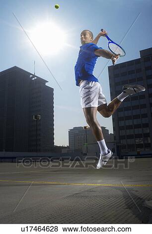 Tennis player jumping on rooftop court View Large Photo Image Stock Photo - Tennis player jumping on rooftop court. Fotosearch