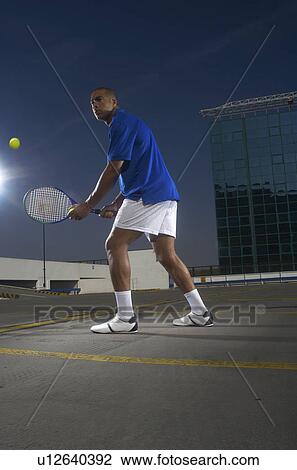 Tennis player on rooftop court View Large Photo Image Stock Image - Tennis player on rooftop court. Fotosearch