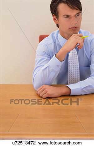 Thinking businessman sitting at desk View Large Photo Image Stock Image - Thinking businessman sitting at desk. Fotosearch