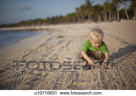 Toddler boy playing with sand on beach View Large Photo Image Stock Image - Toddler boy playing with sand on beach. Fotosearch