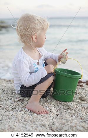 Toddler boy playing with sand on beach View Large Photo Image Stock Photo - Toddler boy playing with sand on beach. Fotosearch