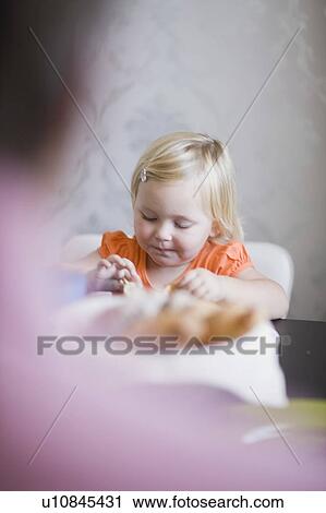 Toddler girl eating at dinner table View Large Photo Image Stock Image - Toddler girl eating at dinner table. Fotosearch