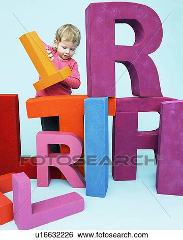 Stock Photograph - Toddler playing with oversize letters. Fotosearch