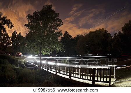 Stock Photograph - Trails of light from mountain bikers. Fotosearch