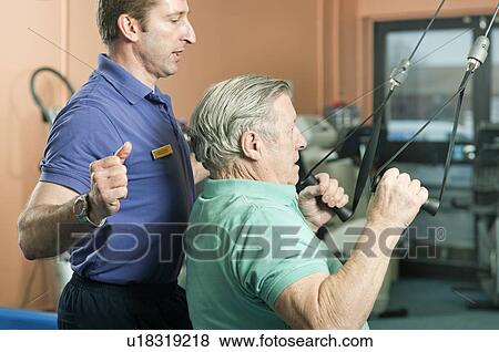 Trainer helping older man exercise View Large Photo Image Stock Photo - Trainer helping older man exercise. Fotosearch