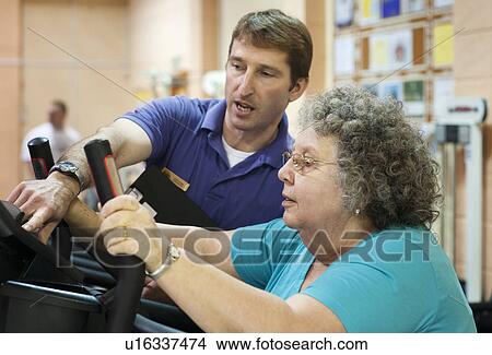 Picture - Trainer helping older woman exercise. Fotosearch