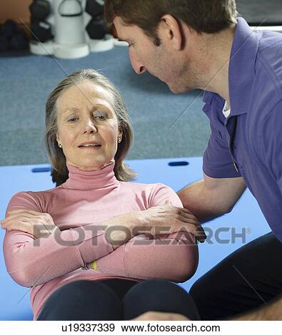 Trainer helping older woman exercise View Large Photo Image Stock Photo - Trainer helping older woman exercise. Fotosearch