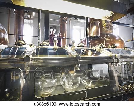 Stock Photo - Whisky pouring from stills in distillery. Fotosearch