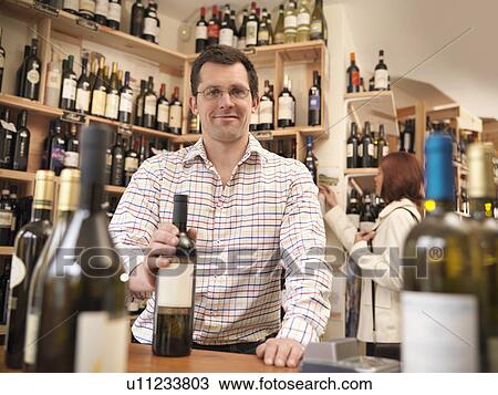 Wine merchant with bottle in shop View Large Photo Image Stock Image - Wine merchant with bottle in shop. Fotosearch