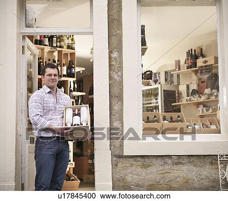 Stock Image - Wine merchant with case of wine in shop. Fotosearch